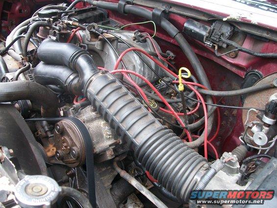 Engine bay with hoses, wires, and engine parts visible