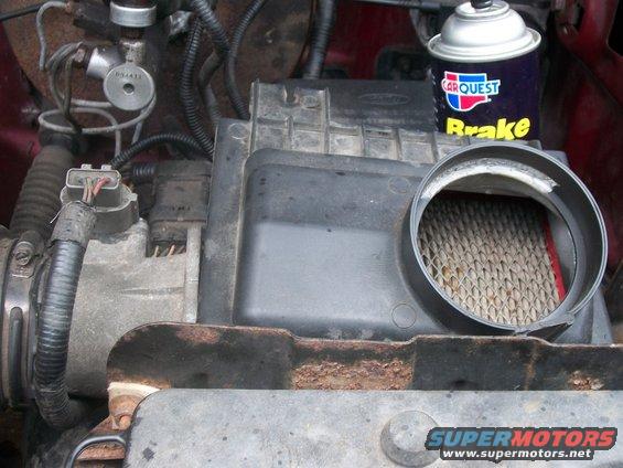 Engine bay showing air filter housing, electrical connectors, and a can of CARQUEST brake cleaner