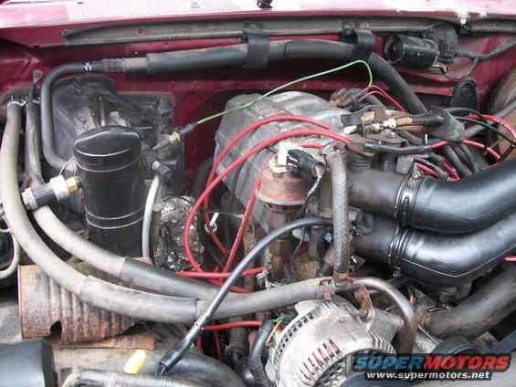 Red engine bay with hoses, wires, and engine components. Water-stained pipes are visible