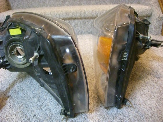 Two vehicle headlights, one with a yellow sticker, resting on carpeted stairs