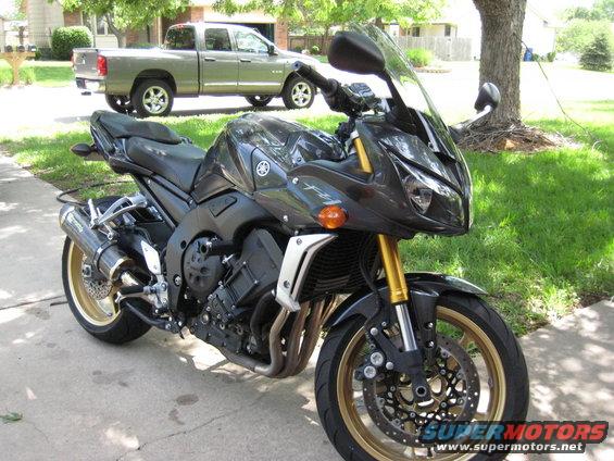 Dark gray Yamaha FZR1000 motorcycle with gold wheels, parked on a driveway