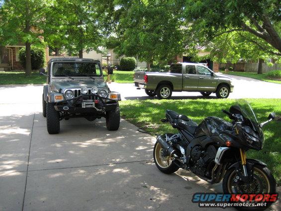 Black sport motorcycle with gold wheels parked on driveway
