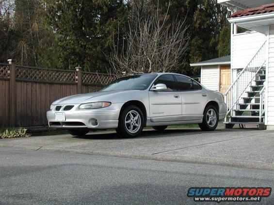 Silver 2002 Pontiac Grand Prix parked on asphalt next to a house with stairs
