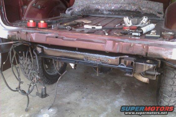 vehicle's rear frame and bumper area with tools and parts on the bed floor