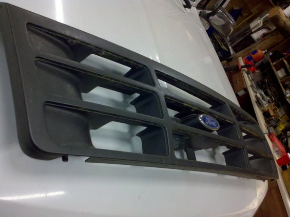Dark gray Ford grille with blue oval emblem, angled view