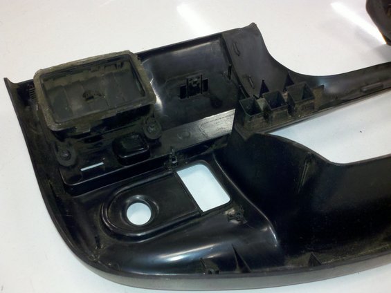 Close-up of a black plastic interior car trim piece with some dust and mounting points