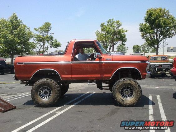 Orange lifted 1978 Ford Bronco side view with chrome trim and large tires