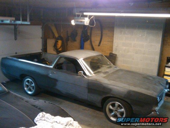 Gray 1969 Ford Ranchero in a garage, primer finish, aftermarket wheels, driver's side visible