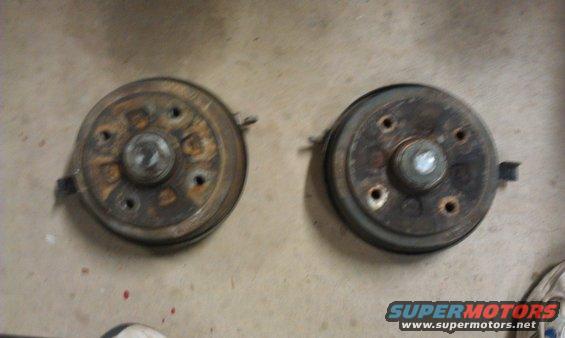 Two rusty brake drums on a concrete surface