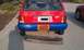 1991 Ford Festiva - The rear of a red and blue 1991 Ford Festiva is shown, with a detached bumper lying in front of it.