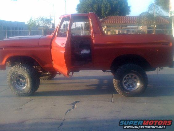 Orange 1978 Ford Bronco, doors open, side view. Lifted suspension and off-road tires visible