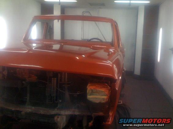 Orange 1978 Ford Bronco cab in paint booth, hood and fenders removed