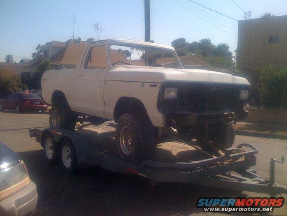 White 1978 Ford Bronco on a trailer, front bumper removed, side view
