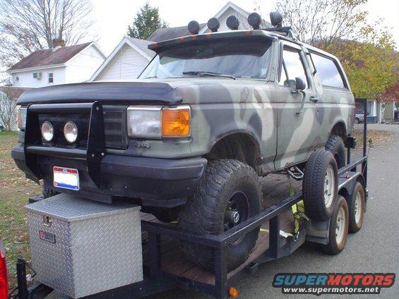 1990 Ford Bronco with camouflage paint on a trailer, front bull bar and roof lights