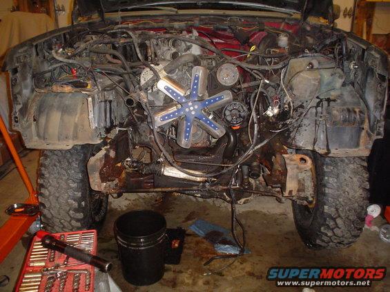 Vehicle engine bay with fan and wiring exposed, under repair