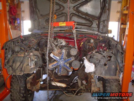 Ford Bronco engine bay with engine removed, supported by an engine hoist