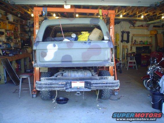 1990 Ford Bronco in garage with engine hoist, camouflage paint