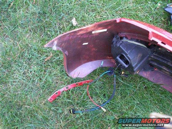 Red car bumper with exposed wiring and black housing