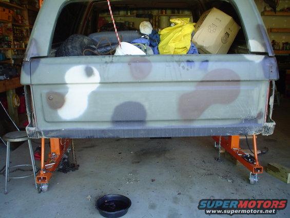 Rear of a camouflaged SUV on jack stands, tailgate open, with cargo inside