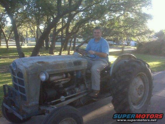 Gray tractor with large rear tires and a man driving