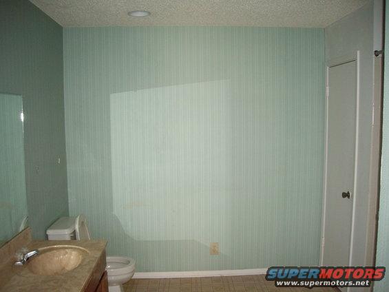 Bathroom with sink, toilet, and door. Light green striped wallpaper