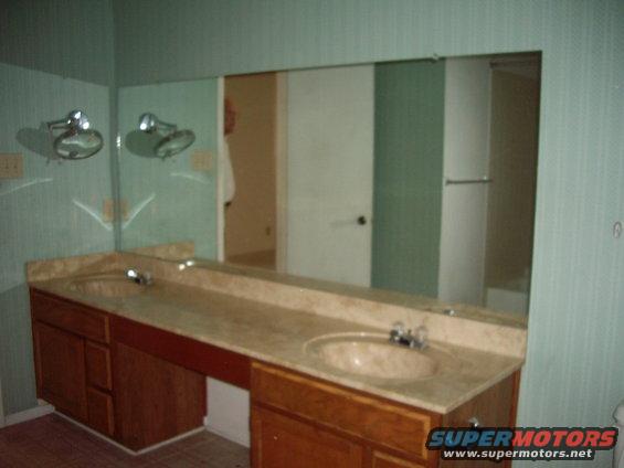 Bathroom vanity with double sinks, marble countertop, and wood cabinets