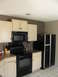 1983 Ford 427 - Interior view of a kitchen cream cabinetry, a black stove, and a black refrigerator.
