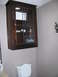 1983 Ford 427 - A wooden bathroom cabinet hangs above a toilet, containing toilet paper and other items.