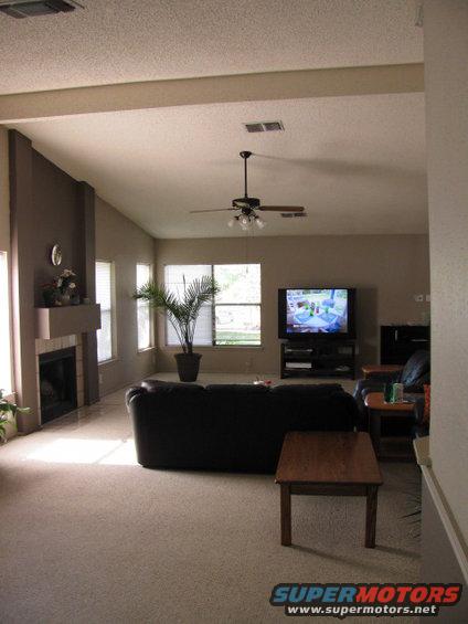 Living room with fireplace, couch, coffee table, and TV. Watermark reads SUPERMOTORS
