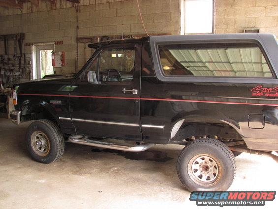 Black 1995 Ford Bronco side view with red pinstripes and 4x4 decal