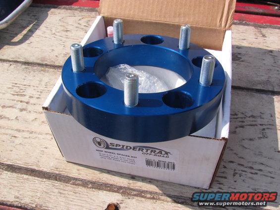 Blue aluminum wheel spacer kit with five studs, in a cardboard box. Text on box reads 'SPIDER TRAX OFF-ROAD'