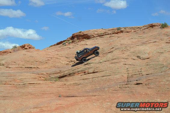 Brown 1986 Ford Bronco II climbing a steep, rocky slope under a blue sky