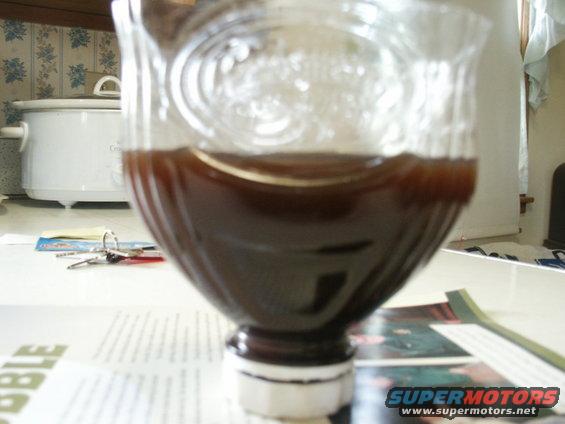 Bottle with dark liquid on a table with keys and a slow cooker in the background