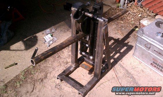 Metal pipe bender with a long tube inserted, on dirt ground