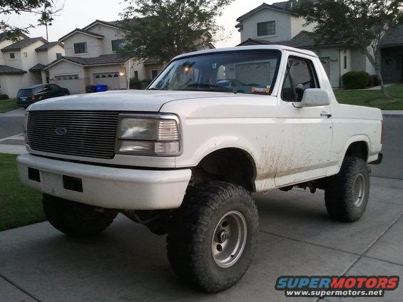White Ford Bronco with aftermarket wheels and tires, lifted suspension, and dirty body panels