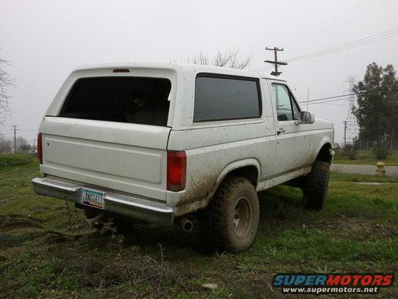 White 1986 Ford Bronco rear 3/4 view, muddy exterior, license plate ANG4611