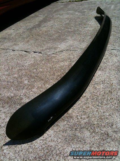 Black plastic fender flare on concrete. Some text is visible on the flare