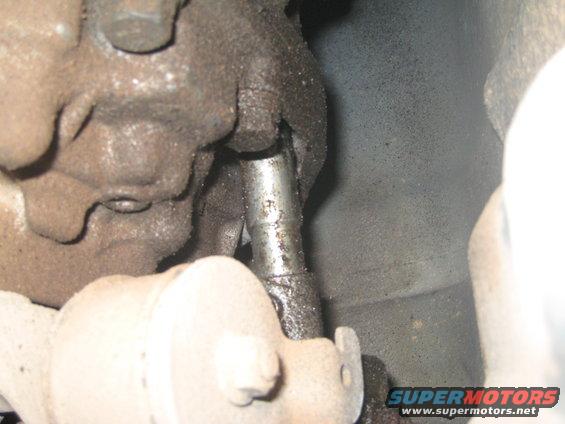 Close-up of a greasy metal shift linkage with bolts and housing