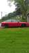 1993 Ford Probe - A red 1993 Ford Probe coupe is seen from the side, parked in a grassy area next to a building.