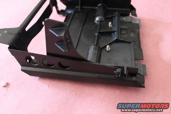 Black plastic and metal automotive part with mounting posts and holes