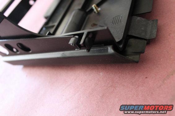 Close-up of a black plastic car interior component with visible clips and mounting points