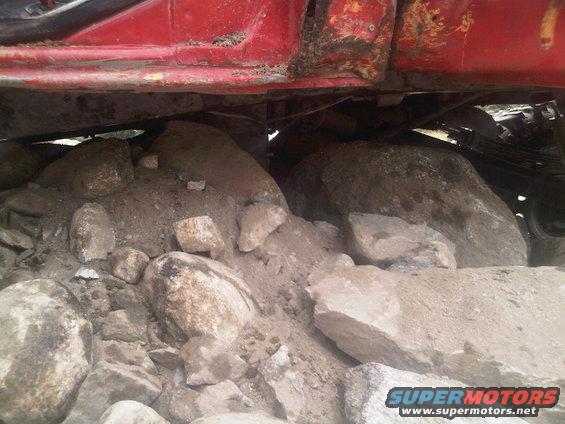 Undercarriage of red vehicle stuck on rocks