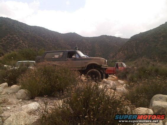 Brown Ford Bronco with off-road modifications parked on a rocky trail