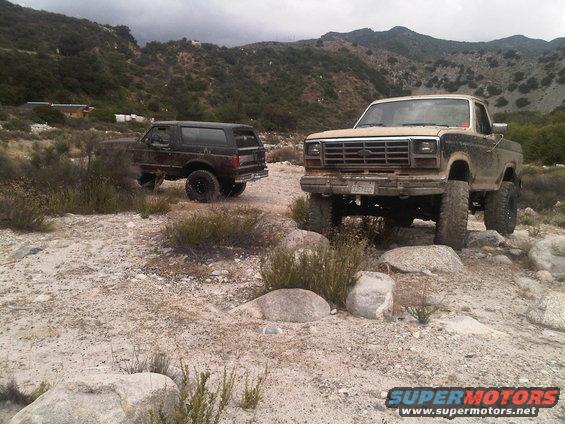 Tan 1980s Ford F-Series truck and dark Bronco off-road