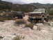 1986 Ford Bronco - Two Ford trucks, a Bronco and an F-Series, are parked off-road in a dusty, mountainous area.