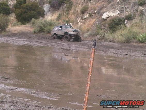 Modified Ford Bronco navigating a muddy trail with lifted suspension and off-road tires