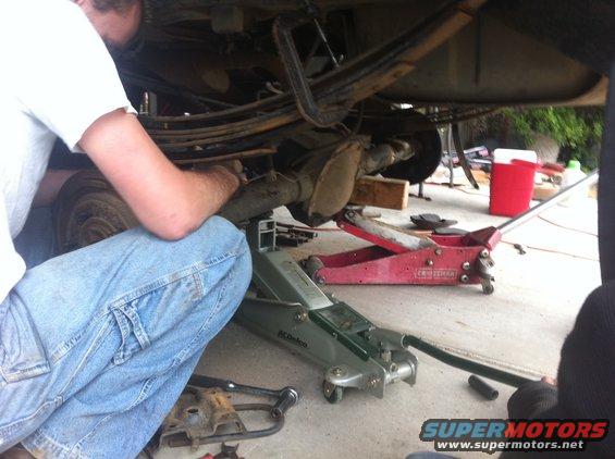 Person working on rear axle of a vehicle supported by floor jacks