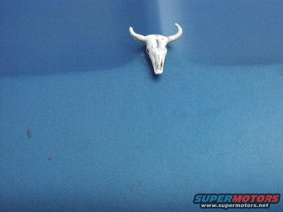 White bull skull emblem on a blue surface. Supermotors.net logo in lower right