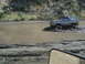 1986 Ford Bronco - A lifted Ford Bronco navigates a muddy terrain, kicking up water and dirt.