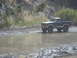 1986 Ford Bronco - This lifted 1980s Ford Bronco navigates a muddy trail, kicking up water as it goes.